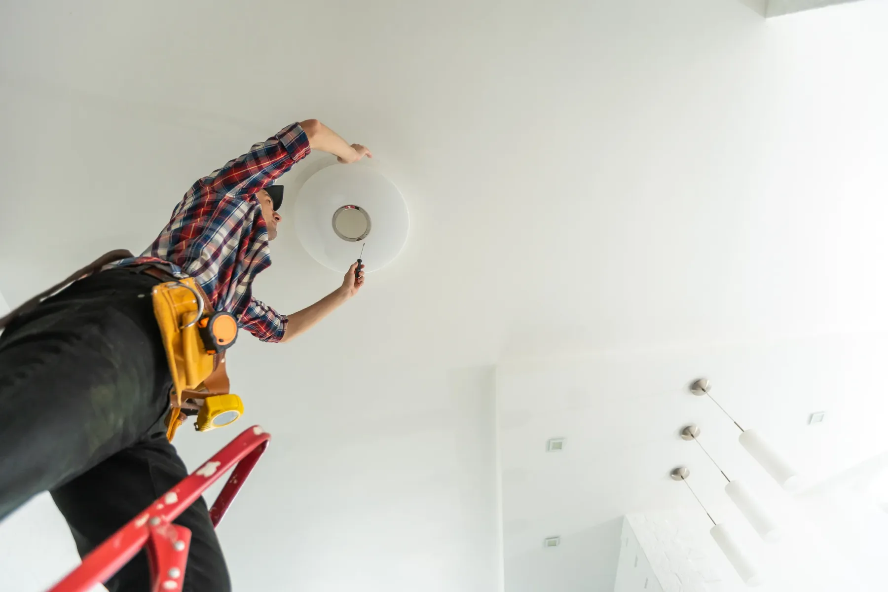 Technician on a stepladder installing an indoor ceiling light.