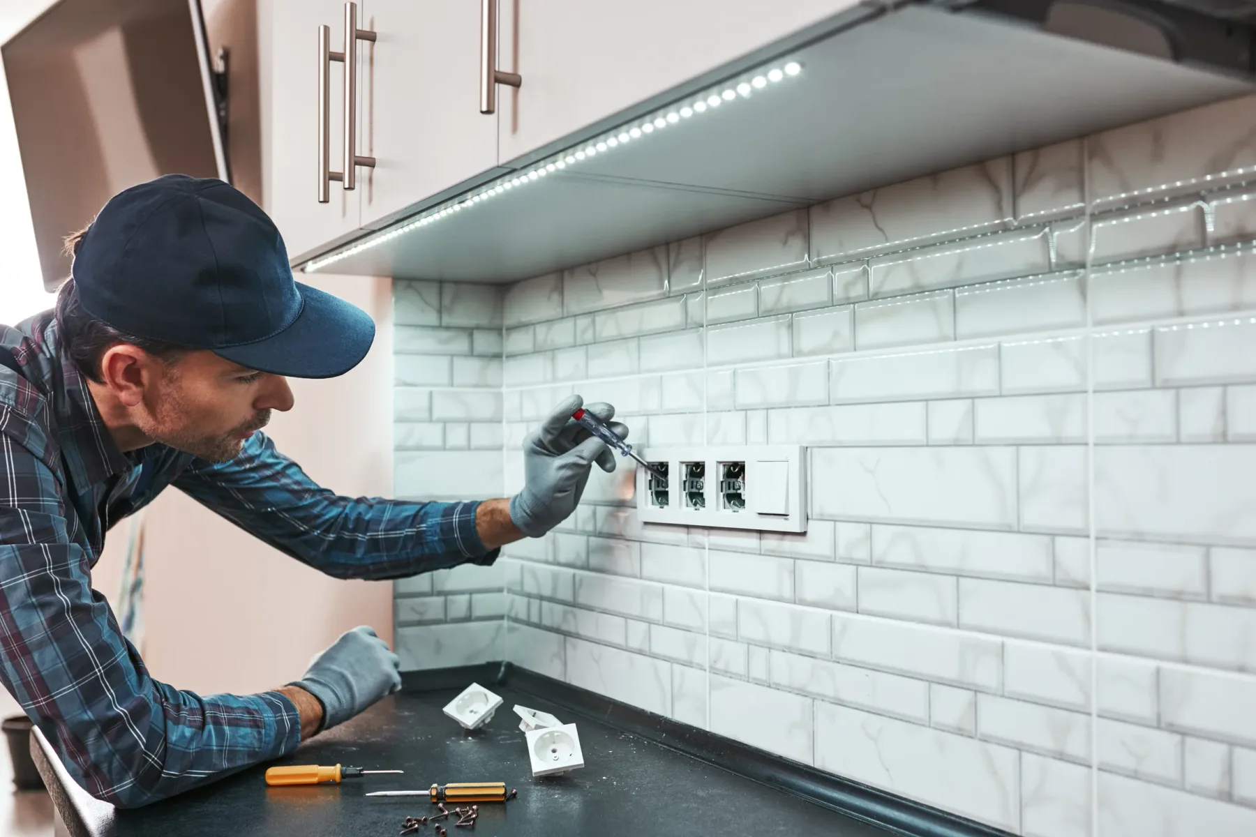 Technician repairing kitchen electrical outlets and switches.