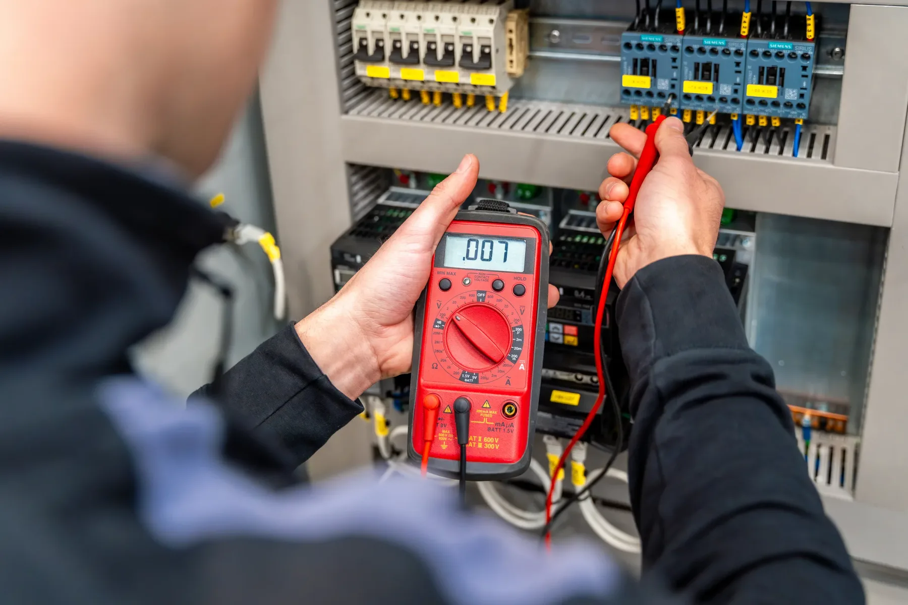 Electrician measuring voltage with a digital multimeter.