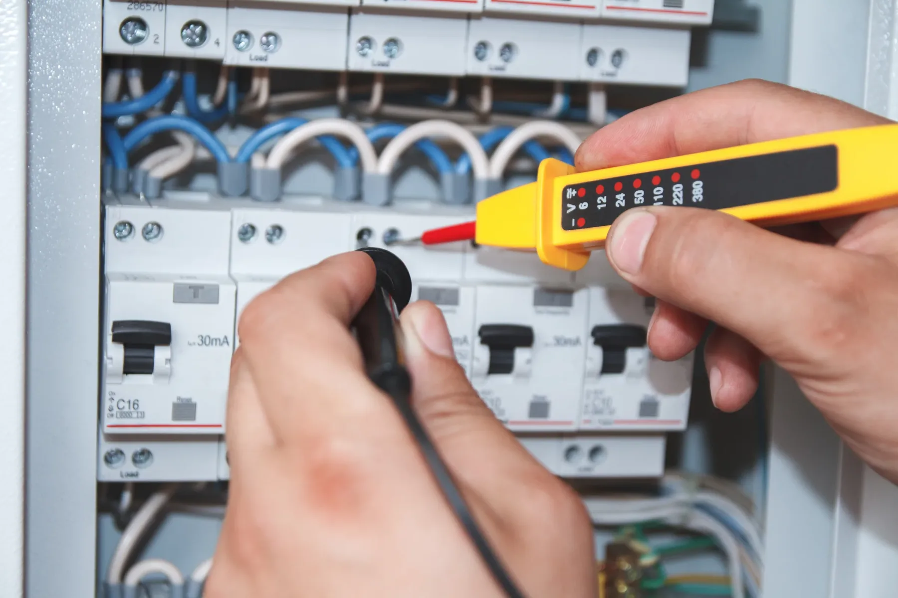 Technician testing electrical panel equipment.
