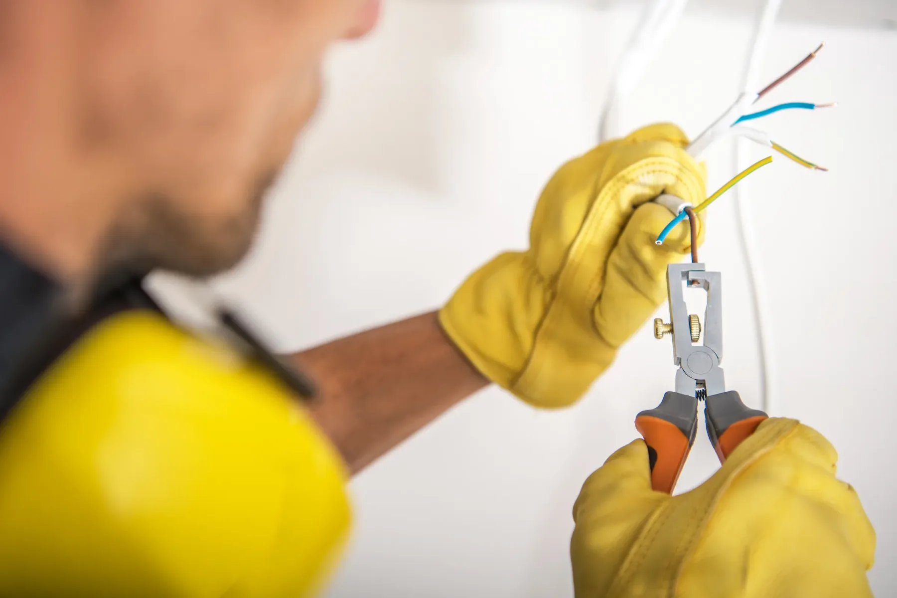 Electrician repairing wiring while wearing protective equipment.